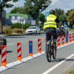Radfahrer mit Warnweste auf durch orange-weisse HORIZONT Leitboys abgetrennter Velospur